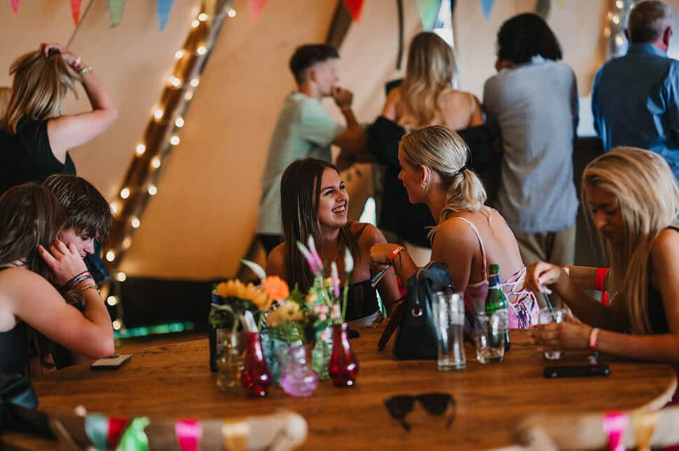 People smiling under a tipi at a Hardy's Catering event